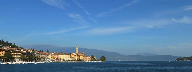 Trip Irland beliebte Urlaubsziele am Gardasee -  Mit einer Fläche von 370 km² ist der Gardasee der größte See Italiens. Es liegt am Fuße der Alpen und erstreckt sich über drei Staaten: Lombardei, Venetien und Trentino. Die maximale Tiefe des Sees beträgt 346 m, er hat eine längliche Form und sein nördliches Ende ist sehr schmal. Dort ist der See von den Bergen der Gruppo di Baldo umgeben. Du trittst aus deinem gemütlichen Hotelzimmer und es begrüßt dich die warme italienische Sonne. Du blickst auf den atemberaubenden Gardasee, der in zahlreichen Blautönen schimmert - von tiefem Dunkelblau bis zu funkelndem Türkis. Majestätische Berge umgeben dich, während die Brise sanft deine Haut streichelt und der Duft von blühenden Zitronenbäumen deine Nase kitzelt. Du schlenderst die malerischen, engen Gassen entlang, vorbei an farbenfrohen, blumengeschmückten Häusern. Vereinzelt unterbricht das fröhliche Lachen der Einheimischen die friedvolle Stille. Du fühlst dich wie in einem Traum, der nicht enden will. Jeder Schritt führt dich zu neuen Entdeckungen und Abenteuern. Du probierst die köstliche italienische Küche mit ihren frischen Zutaten und verführerischen Aromen. Die Sonne geht langsam unter und taucht den Himmel in ein leuchtendes Orange-rot - ein spektakulärer Anblick.